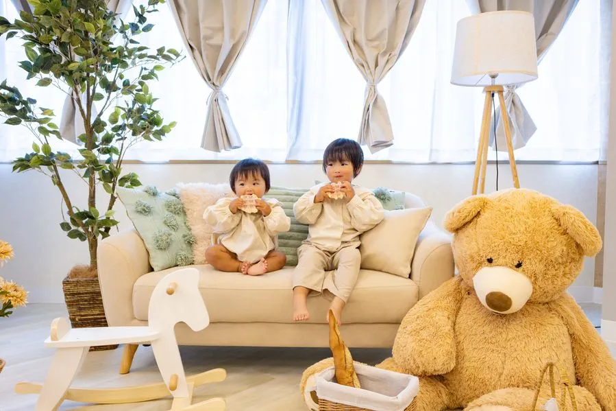 ソファに座る子どもたちと大きなくまのぬいぐるみ。プレゼント交換の実施写真ではありません